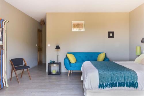 a bedroom with a bed and a blue couch at Le Ruone in Calcatoggio