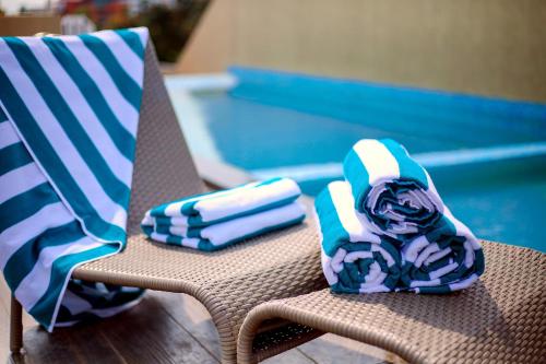 two towels sitting on a chair next to a swimming pool at Sidra Pristine Hotel and Portico Halls in Cochin