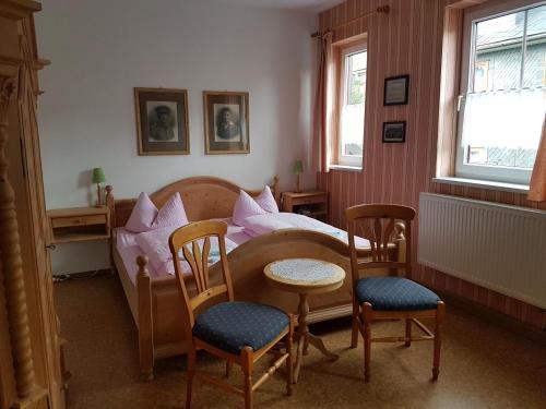a bedroom with a bed with a table and chairs at Gasthaus und Hotel Peterhänsel in Spechtsbrunn