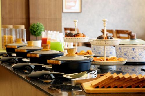 a buffet with bowls and plates of food on a counter at Sidra Pristine Hotel and Portico Halls in Cochin