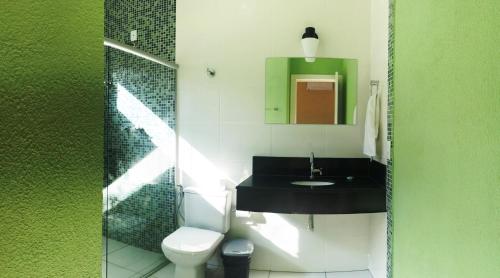 W łazience znajduje się umywalka, toaleta i lustro. w obiekcie Vila Mantilla Pousada w mieście Três Marias