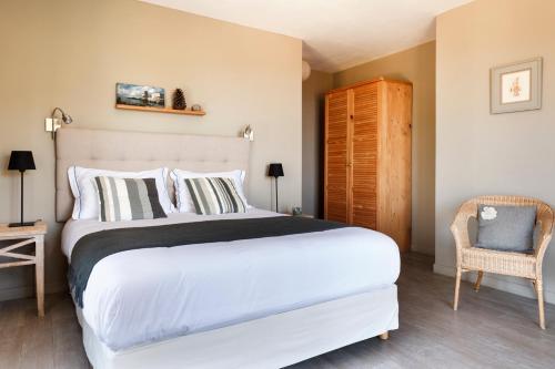 a bedroom with a large white bed and a chair at Le Ruone in Calcatoggio
