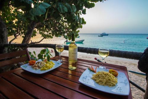 a table with two glasses of wine and pasta on the beach at Paradise Island Beach Resort in Punta Rucia