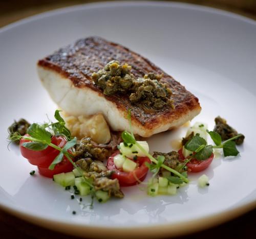 a white plate with a piece of fish and vegetables at Aroma Angkor Boutique Hotel in Siem Reap