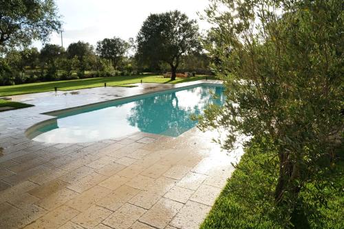 a swimming pool with blue water in a park at Masseria Li Reni in Manduria