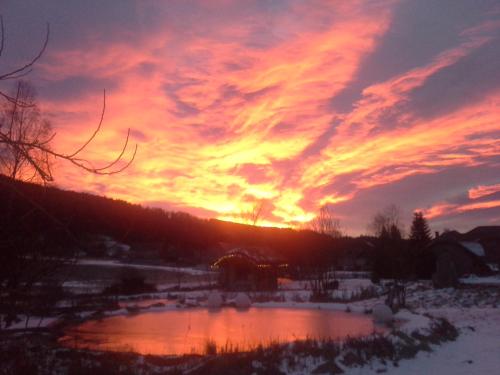 a sunset over a pond in the snow at Pension Gruber in Weisspriach