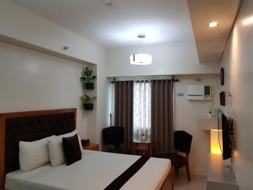 um quarto de hotel com uma cama, uma mesa e cadeiras em Studio Unit at The Beacon Makati em Manilla
