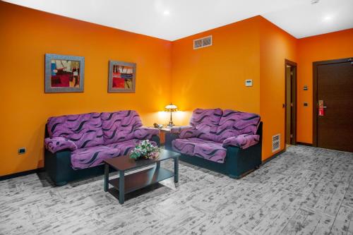 two purple couches in a room with orange walls at Hotel Moya in Honrubia