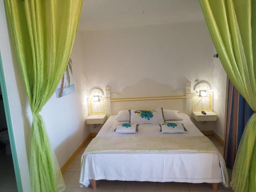 sypialnia z łóżkiem z 2 lampami i zielonymi zasłonami w obiekcie les hauts de caritan w mieście Sainte-Anne