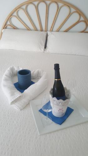 a bottle of wine and a glass on a bed at Maison Tizi in Passoscuro
