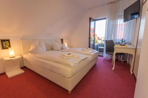 Habitación de hotel con cama blanca grande y escritorio. en Hotel Rosengarten en Schwäbisch Gmünd