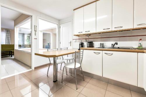 a kitchen with white cabinets and a table and chairs at El Veril del Duque Apartment in Adeje