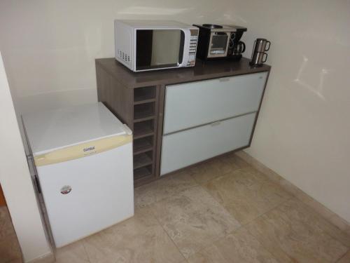 una pequeña cocina con microondas y nevera. en Flat Privado Manaus, en Manaus