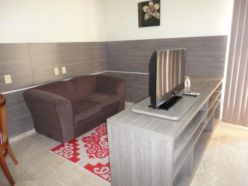 a living room with a couch and a television at Flat Privado Manaus in Manaus
