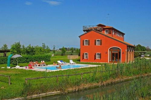 um edifício vermelho com uma piscina ao lado de uma casa em Residence Valle Cavallino em Cavallino-Treporti
