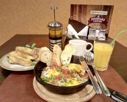 a table with a plate of food with a bowl of eggs and bread at Hotel Lubenska Sloboda in Vilʼshanka