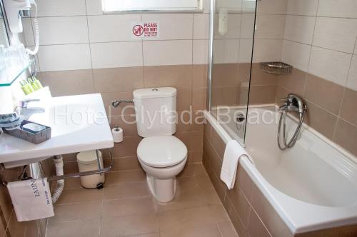 a bathroom with a toilet and a tub and a sink at Glyfada Beach Hotel in Glyfada