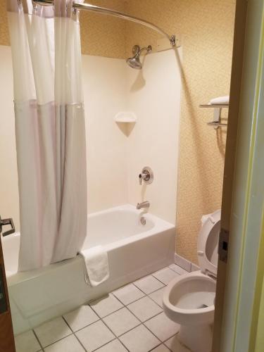 a bathroom with a white tub and a toilet at Days Inn by Wyndham Tulsa Central in Tulsa
