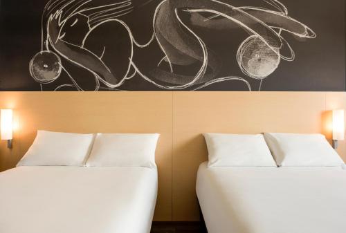 two beds in a room with a painting on the wall at Ibis Culiacan in Culiacán