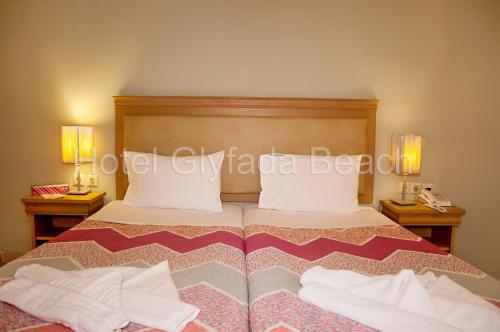 a bedroom with a bed with two nightstands and two lamps at Glyfada Beach Hotel in Glyfada