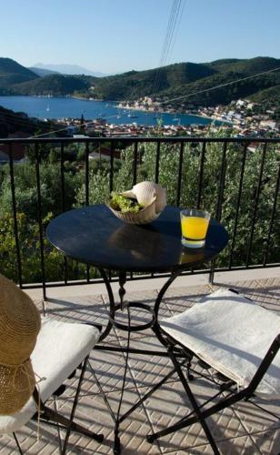 a table with a glass of orange juice on a balcony at Euktimeno in Vathi, Ithaka