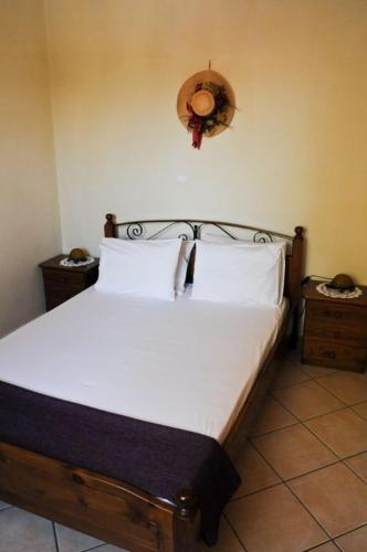 a bed with white sheets and a clock on the wall at Euktimeno in Vathi, Ithaka