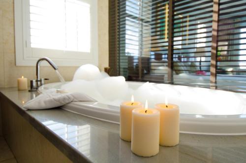 zwei Kerzen auf einer Theke in einem Badezimmer mit Badewanne in der Unterkunft Newstead Belmont Hills Golf Resort & Spa in Mount Pleasant
