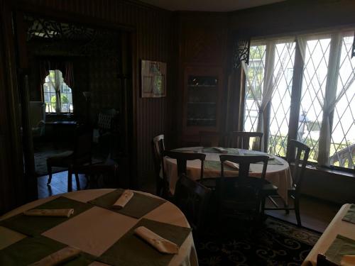 a dining room with two tables and chairs and windows at Inn at the Park in Cape May