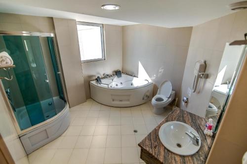 a bathroom with a tub and a toilet and a sink at Hotel Feni in Kavadarci