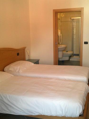 a bedroom with two beds and a bathroom with a sink at Residence Centrale in Dro