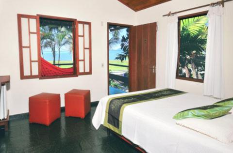 een slaapkamer met 2 bedden, 2 stoelen en ramen bij Pousada Vistamar in Paraty