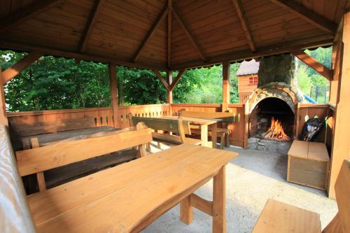 a wooden pavilion with benches and a fireplace at Pokoje i apartamenty u Sabiny - DOSTĘP DO JACUZZI TYLKO W WYBRANYCH OPCJACH sprawdź poniżej szczegóły rezerwacji in Szczawnica