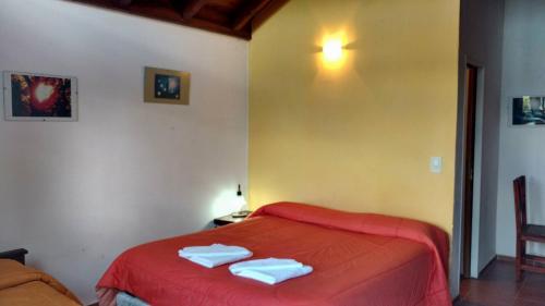a bedroom with a red bed with towels on it at El Mundo Interior in Capilla del Monte