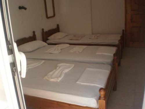 three beds in a room with white sheets and towels at Dimitra in Petra