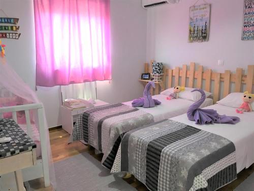 two beds in a bedroom with pink curtains at Your Home in Athens