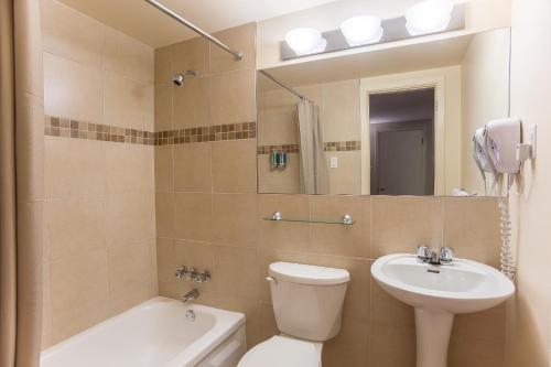 a bathroom with a toilet and a sink and a mirror at Motel Du Fleuve in Brossard