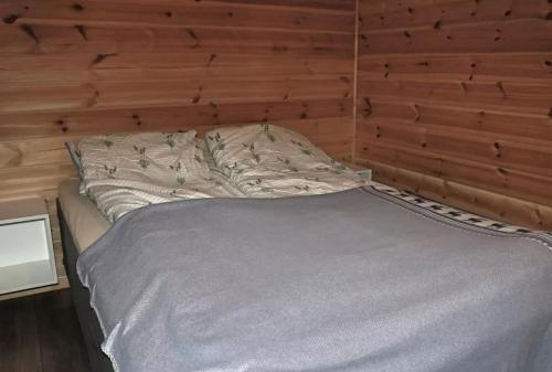 a bed in a room with a wooden wall at Cabin by the river in Storslett