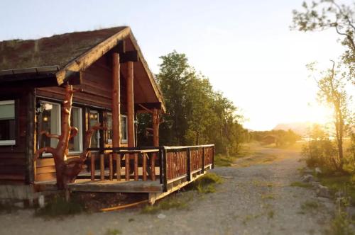 a small cabin with a porch on a dirt road at Cabin by the river in Storslett