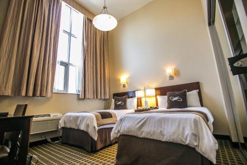 a hotel room with two beds and two windows at Pointe Plaza Hotel in Brooklyn