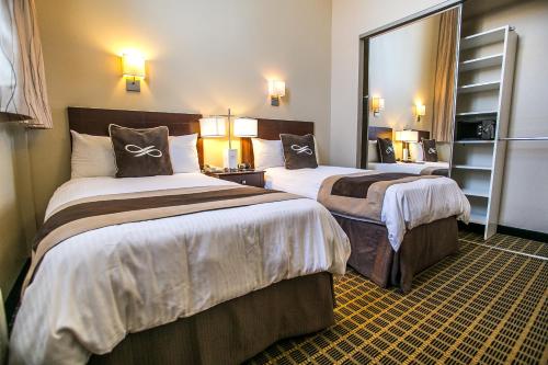 a hotel room with two beds and a mirror at Pointe Plaza Hotel in Brooklyn