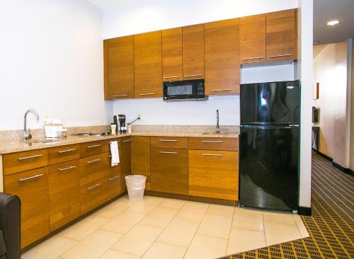 a kitchen with a black refrigerator and wooden cabinets at Pointe Plaza Hotel in Brooklyn