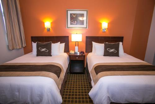 two beds in a hotel room with two lamps at Pointe Plaza Hotel in Brooklyn