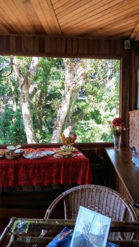 een eetkamer met een tafel en een groot raam bij Aldebaran Pousada in Visconde De Maua