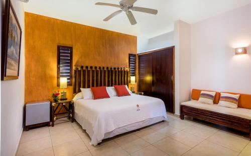 a bedroom with a large white bed and a couch at Hotel Villas El Encanto Cozumel in Cozumel
