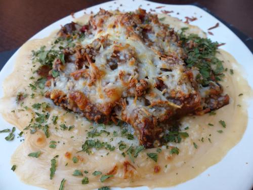 a plate of food with a pizza with cheese at Hostal Vall D'Aneu by Arcas & Sambola in Esterri d'Àneu