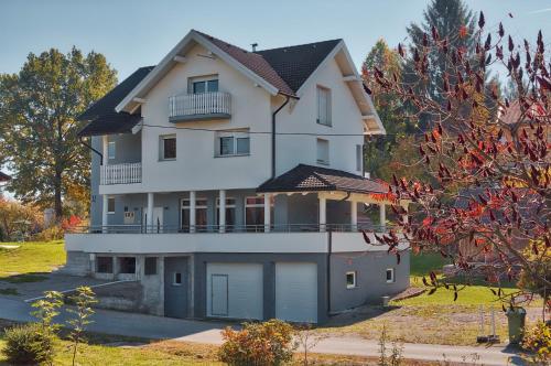 a large white house with a balcony on top at Apartment Snježana in Slunj