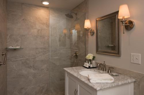 a bathroom with a shower with a sink and a mirror at Harbor House Inn in Sackets Harbor