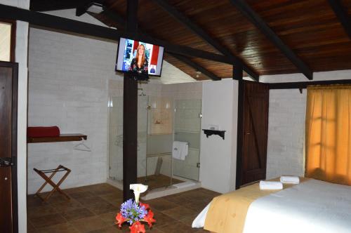 a bedroom with a bed and a tv on a wall at Bosque Protector Hacienda Guamag in Ba&ntilde;os