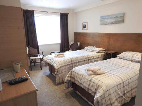 a hotel room with two beds and a desk at Cherish End Guest House in Dunstable