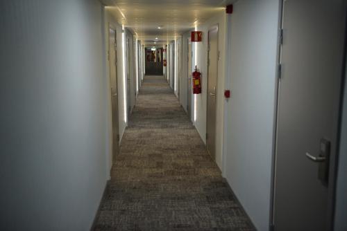 a hallway with white walls and a long hallway with white doors at Hotell Nova in Karlstad